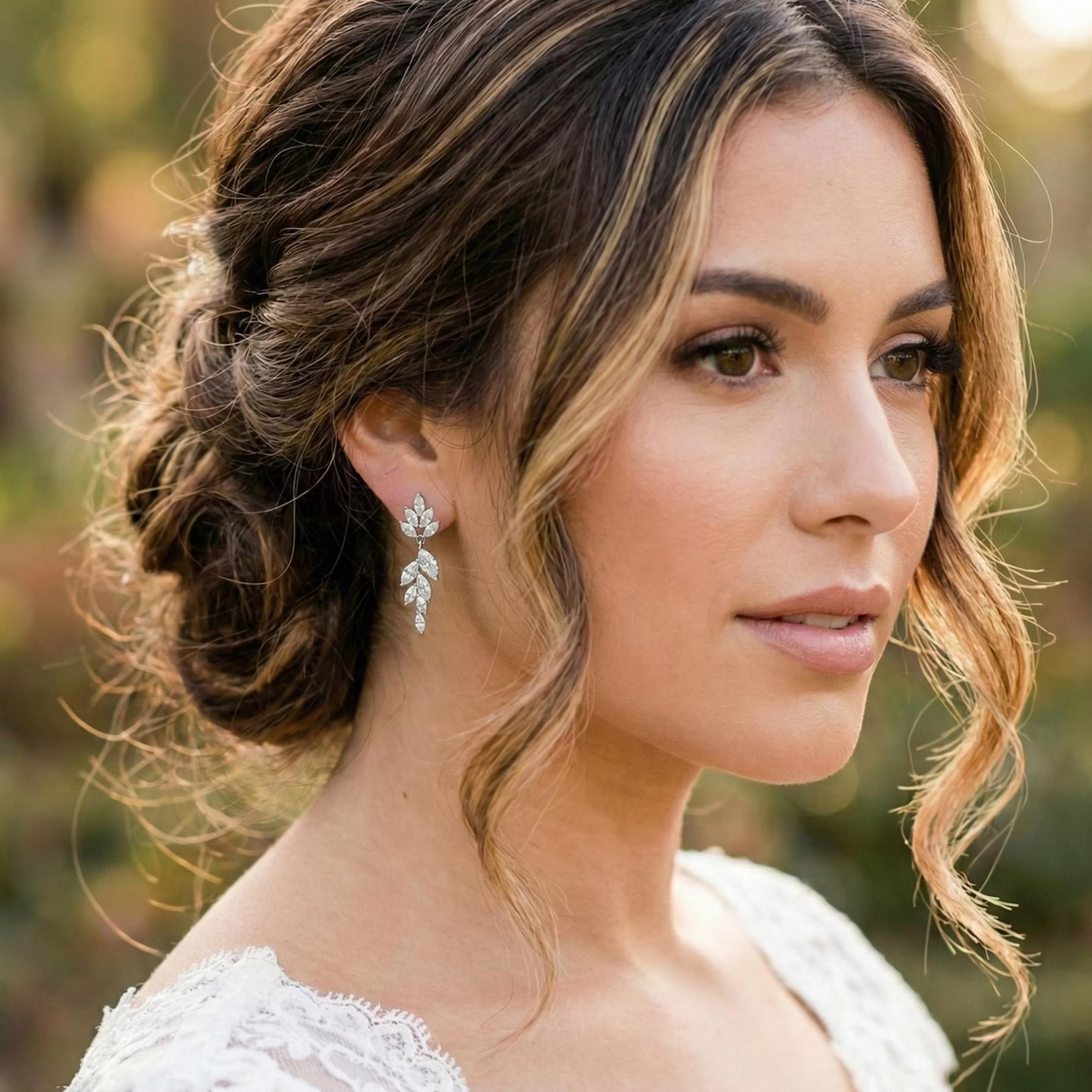 Beautiful bride wearing elegant nature-inspired silver wedding earrings with a cascading floral leaf design.