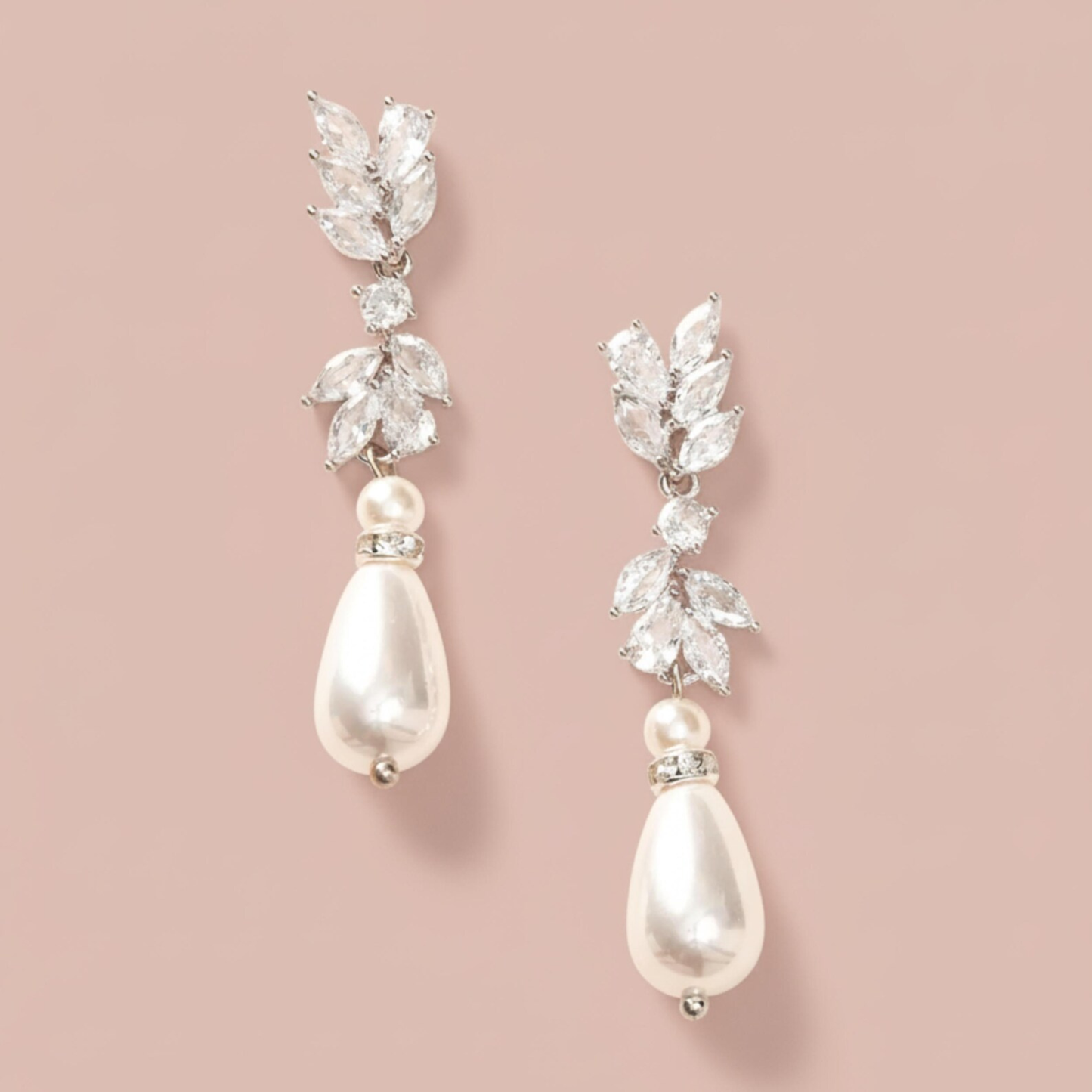 Pair of pearl and crystal drop earrings on a pink background