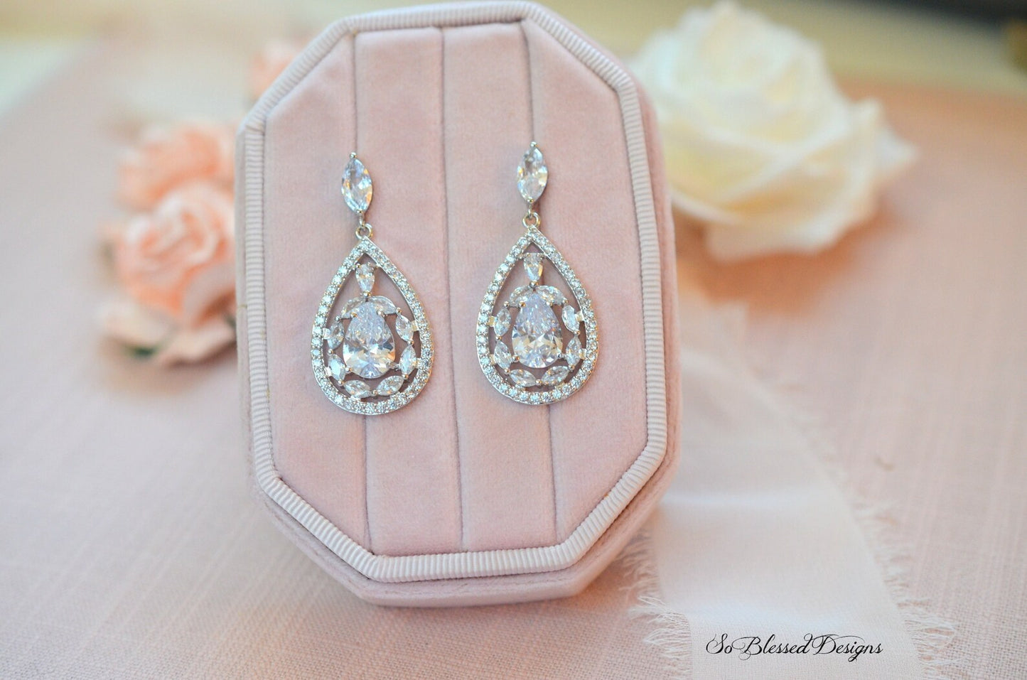 Teardrop-shaped earrings on a pink jewelry box with floral background