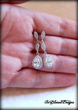 Bride holding long crystal earrings on wedding day 