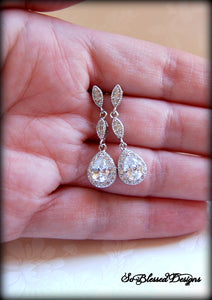 Bride holding long crystal earrings on wedding day 
