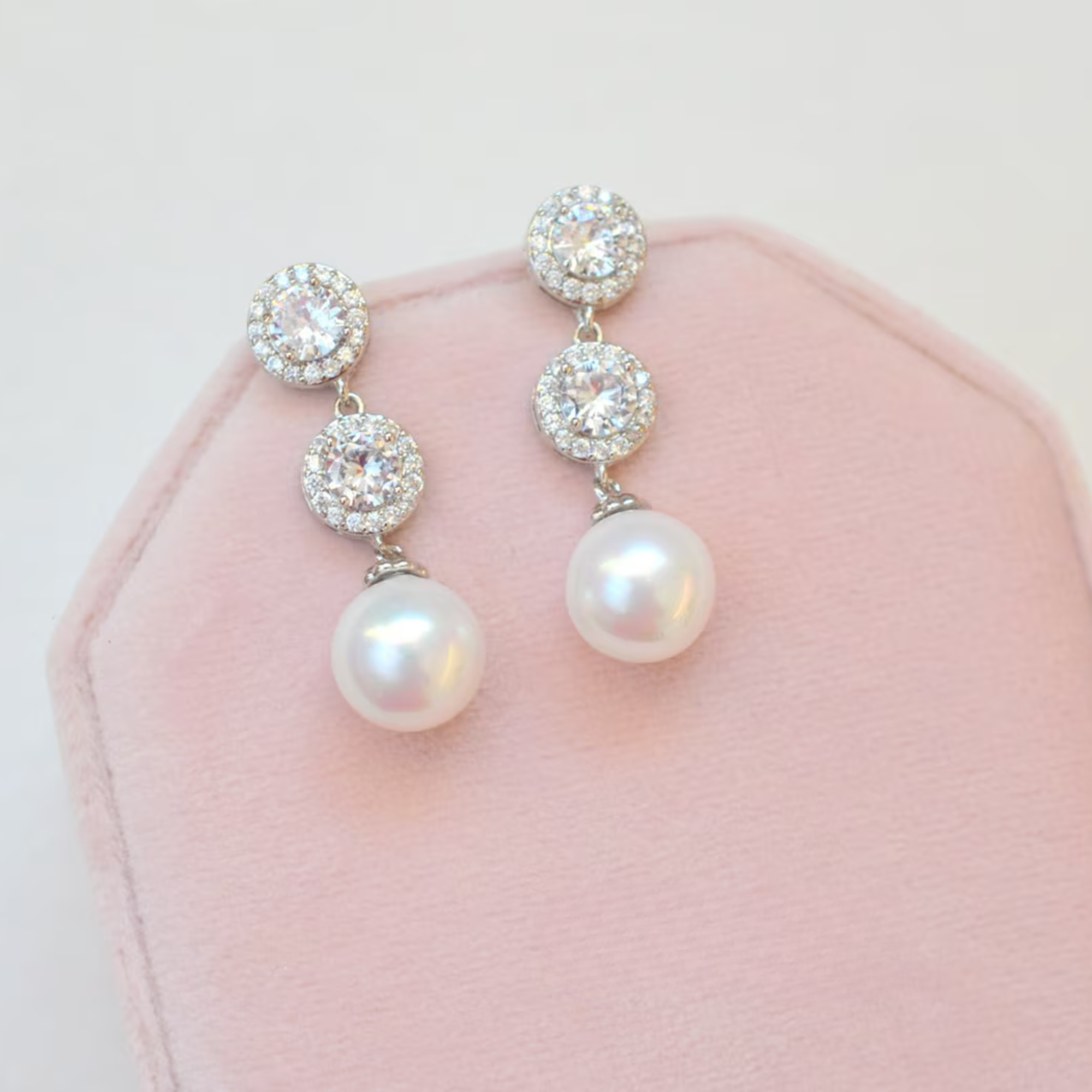 Pearl and crystal earrings on a pink cushion