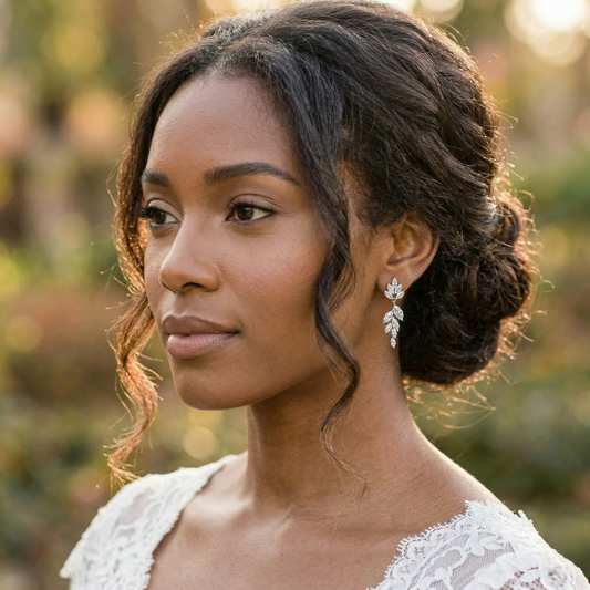 Bride with a romantic updo hairstyle wearing sterling silver CZ floral leaf dangle earrings.
