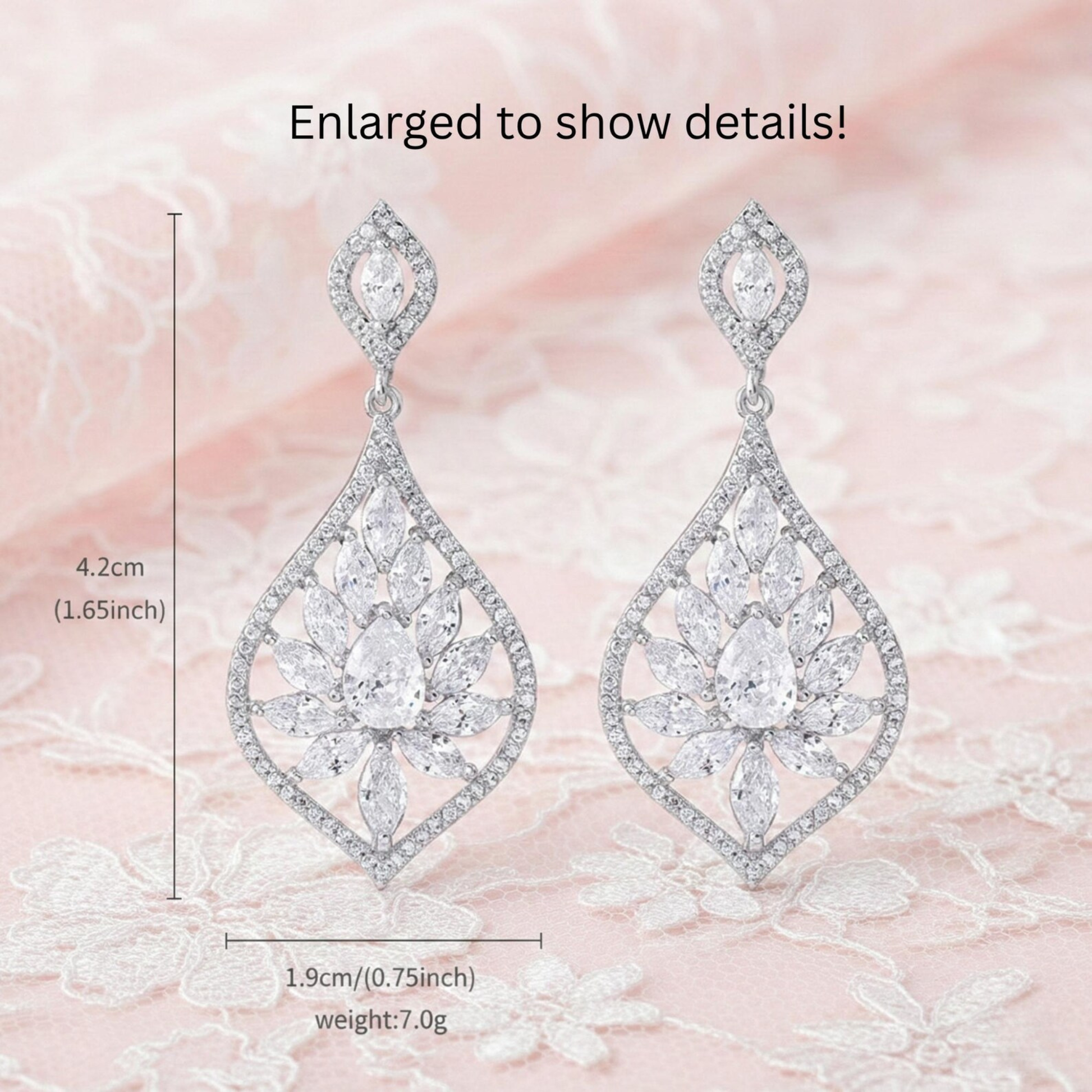 Pair of silver Cubic Zirconia earrings with clear gemstones on a pink floral background