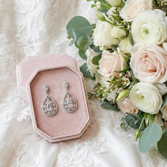 Silver Cubic Zirconia Dangle teardrop earrings in a pink velvet box with a bouquet of flowers on a white lace background