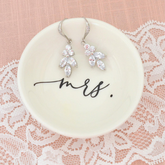 Pair of silver earrings on a 'mrs.' dish with lace background