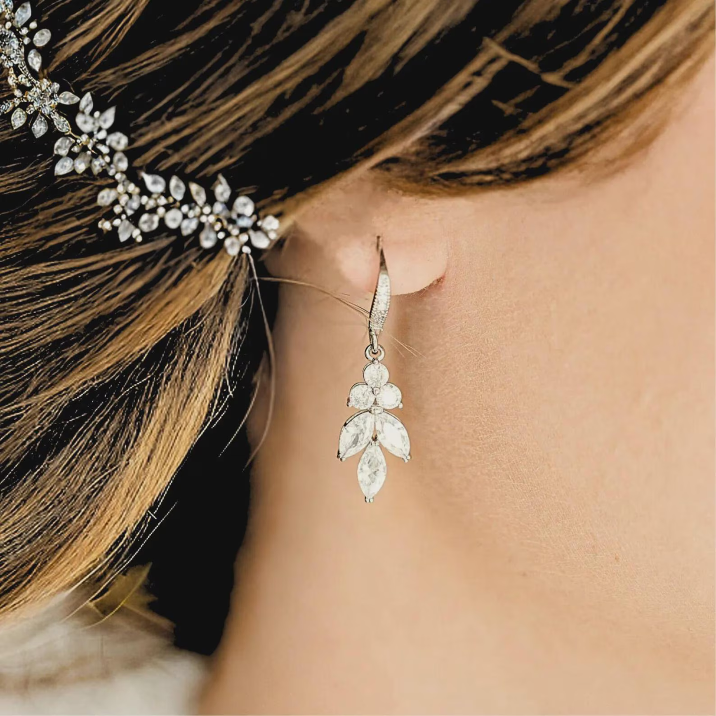 Close-up of a woman wearing a silver Cubic Zirconia dangle earring with a blurred background