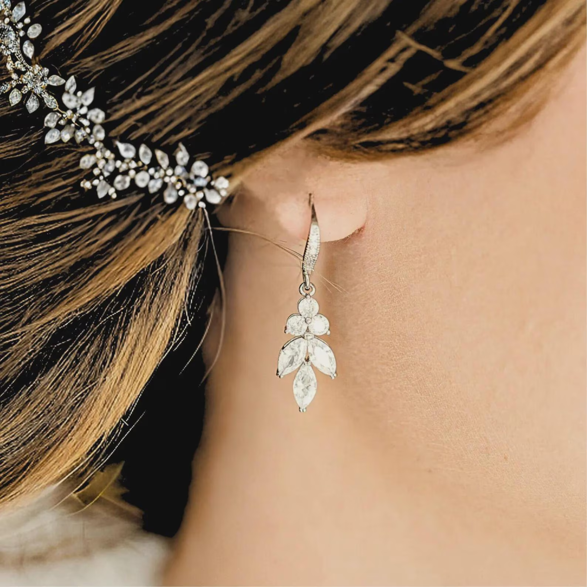 Close-up of a woman wearing a silver Cubic Zirconia dangle earring with a blurred background