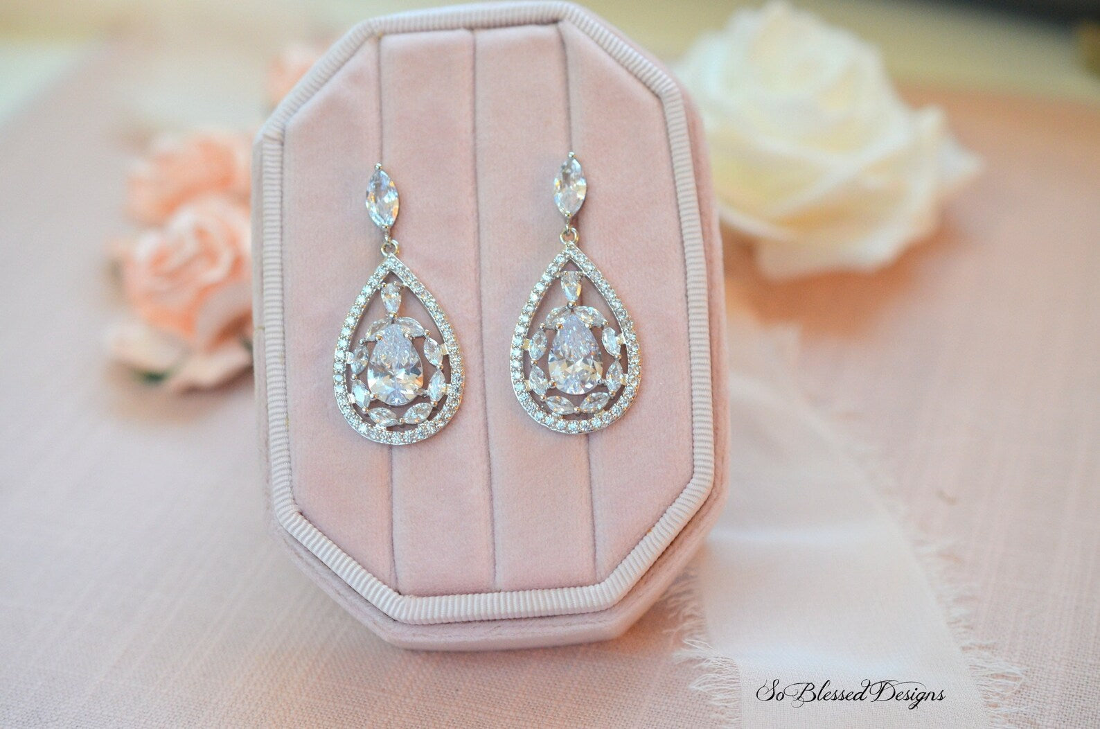 Teardrop-shaped earrings on a pink jewelry box with floral background