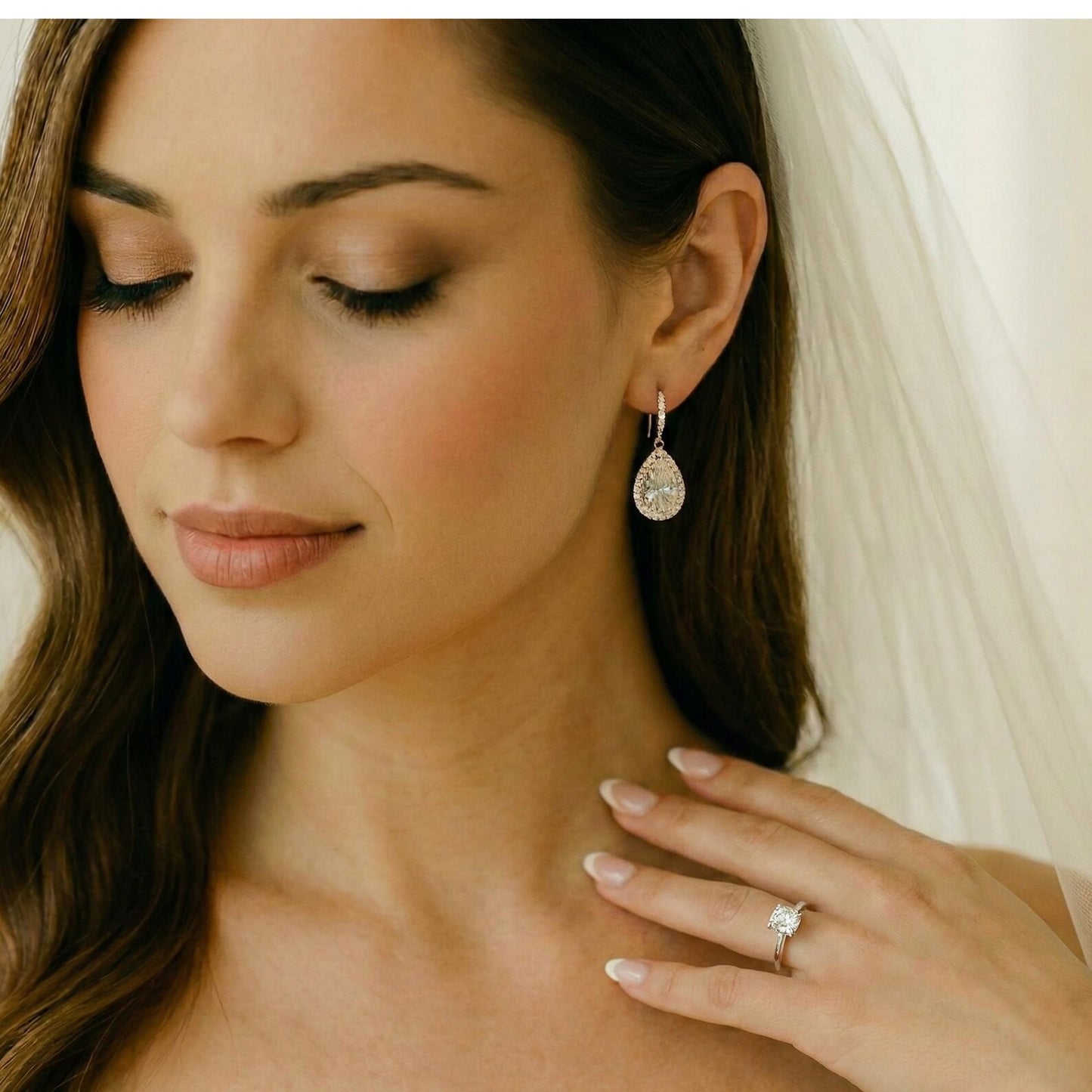 Woman wearing diamond earrings and ring, with a soft focus background