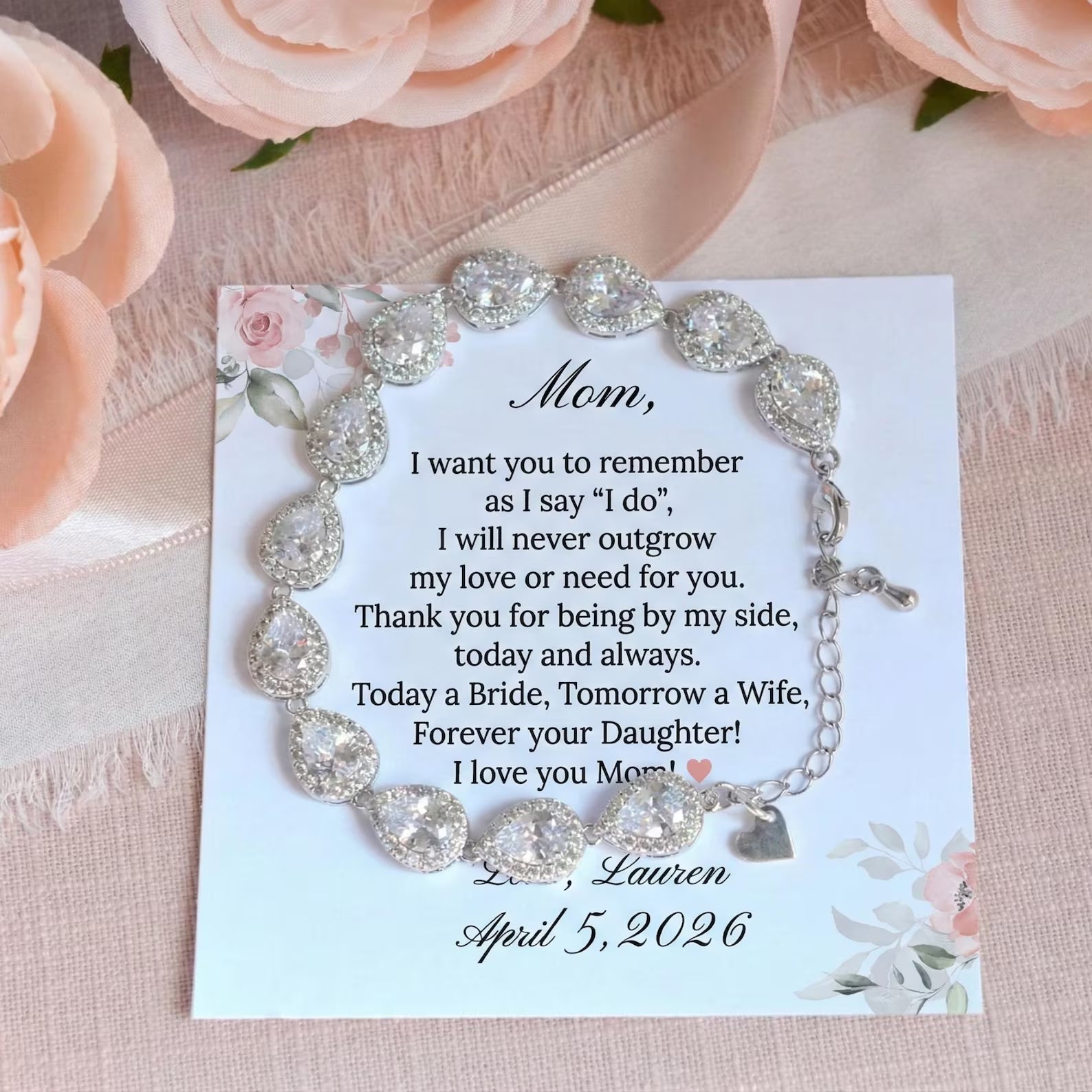 Bracelet with sentimental message on a card, surrounded by pink flowers.