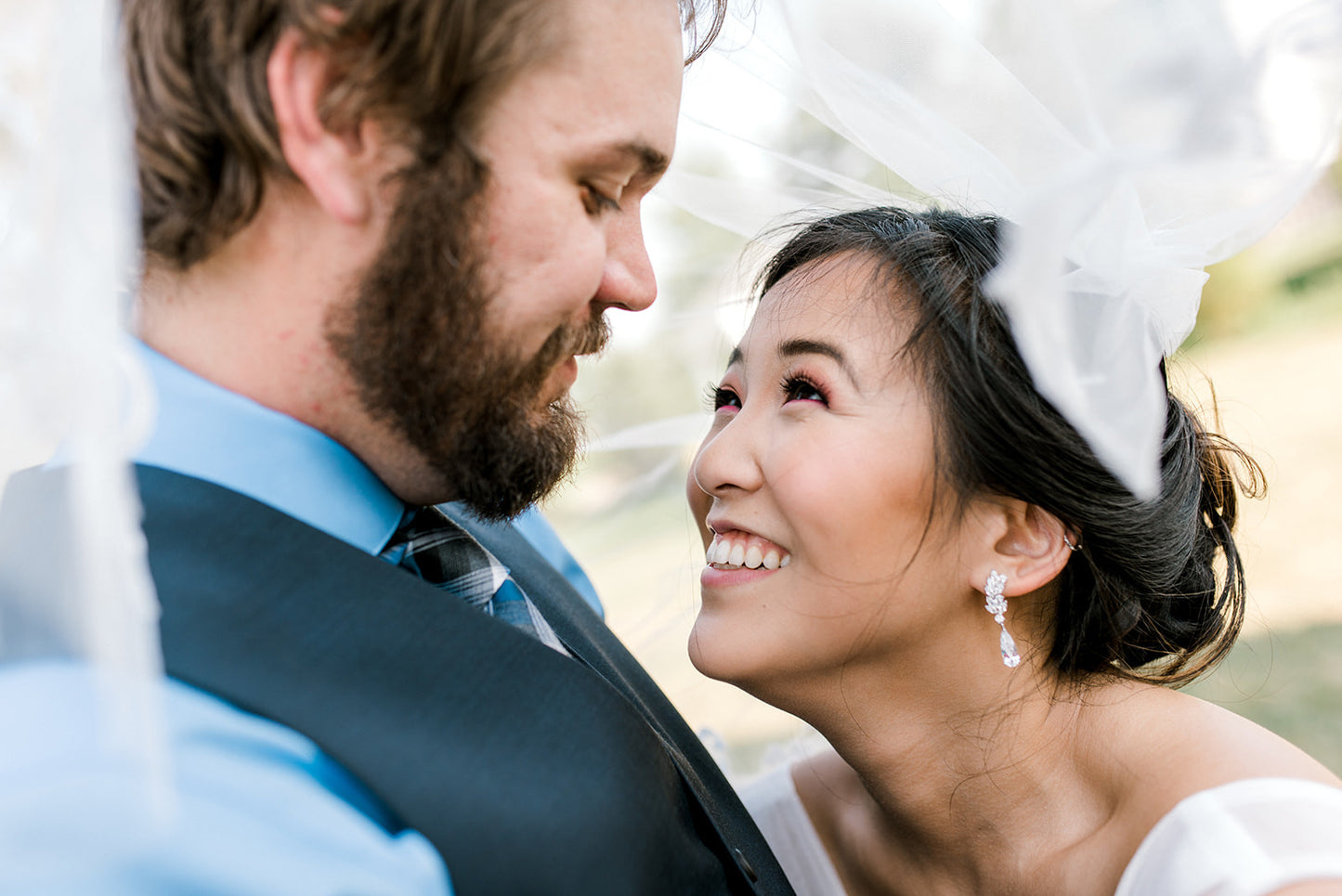 Bride showing off her long crystal bride earrings to groom