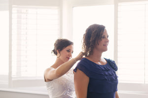 Bride putting necklace on mother of the bride on wedding day