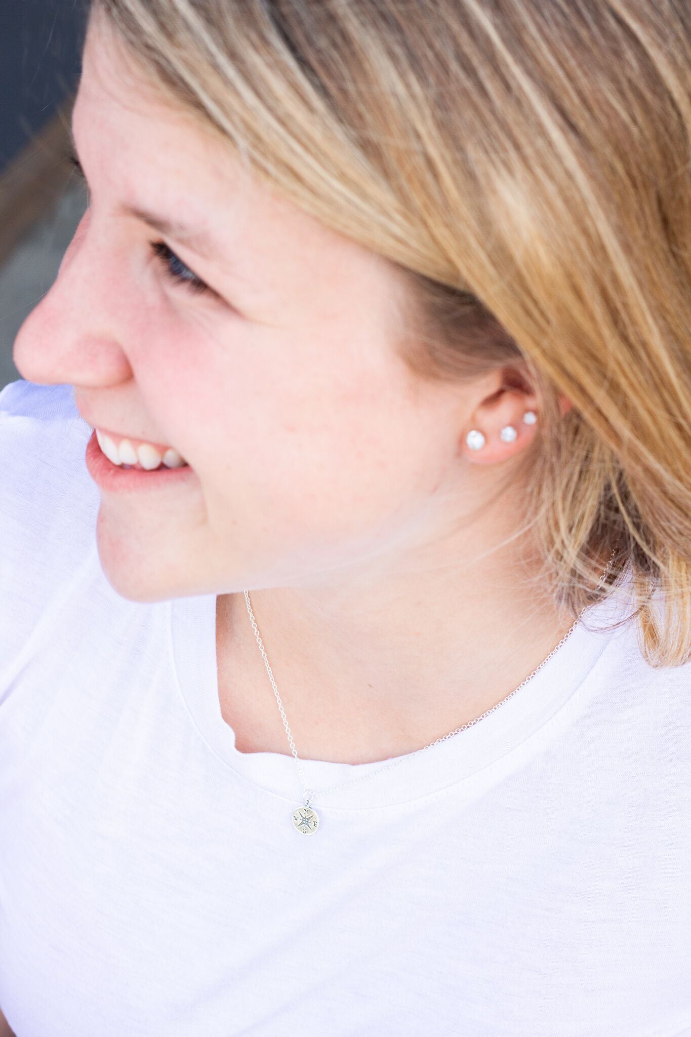 Young girl proudly wearing silver compass necklace