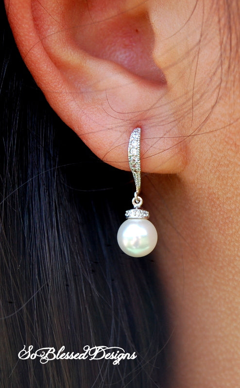 Classic bridal pearl dangle earring with pave crystal details and a white pearl drop, worn on an earlobe.