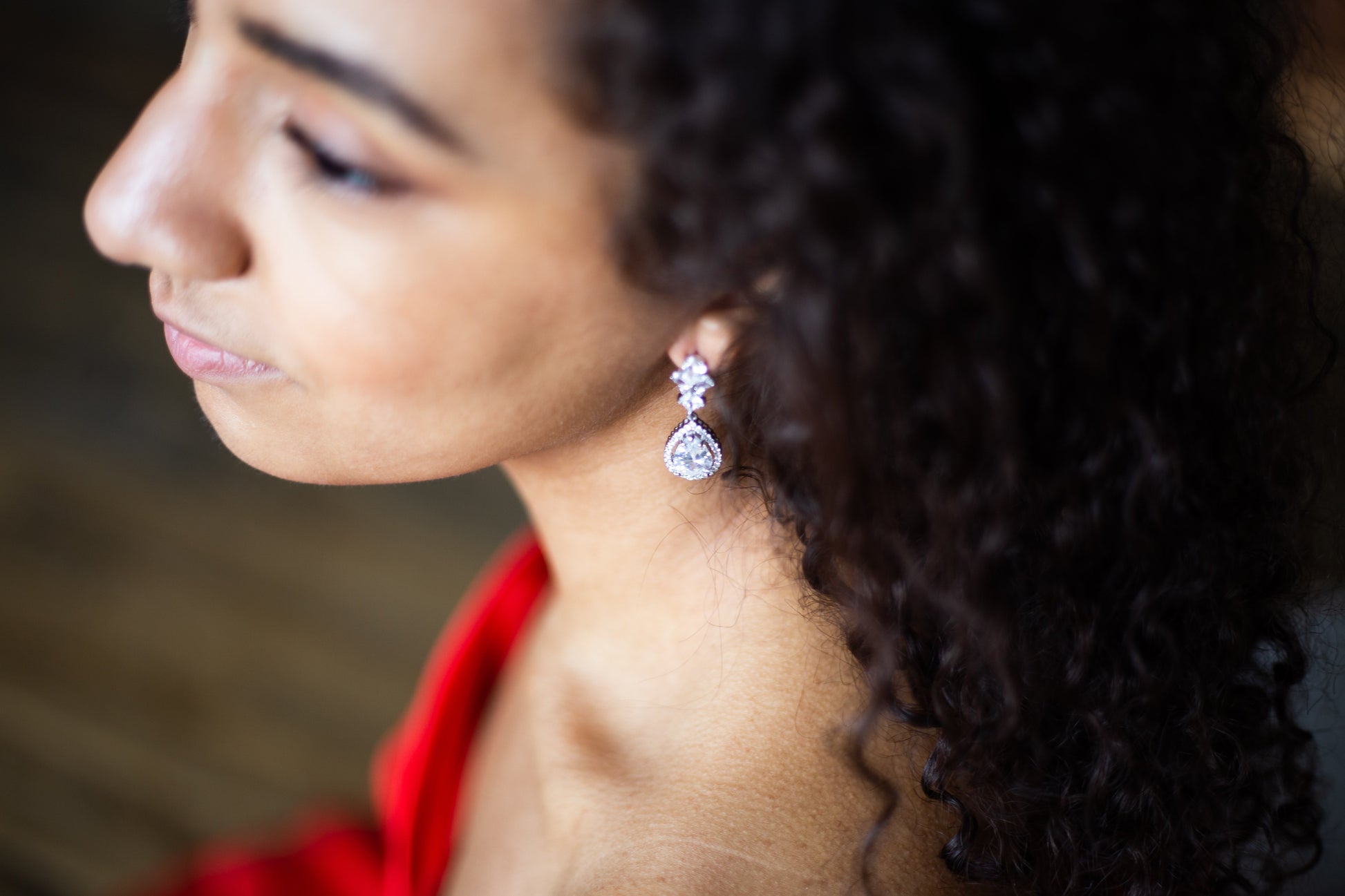 bride putting on marquise teardrop earrings on wedding day