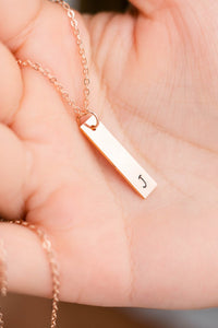 bridesmaid holding rose gold initial necklace in hand