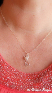 Mother wearing silver connecting hearts necklace with pearl accent on neck 