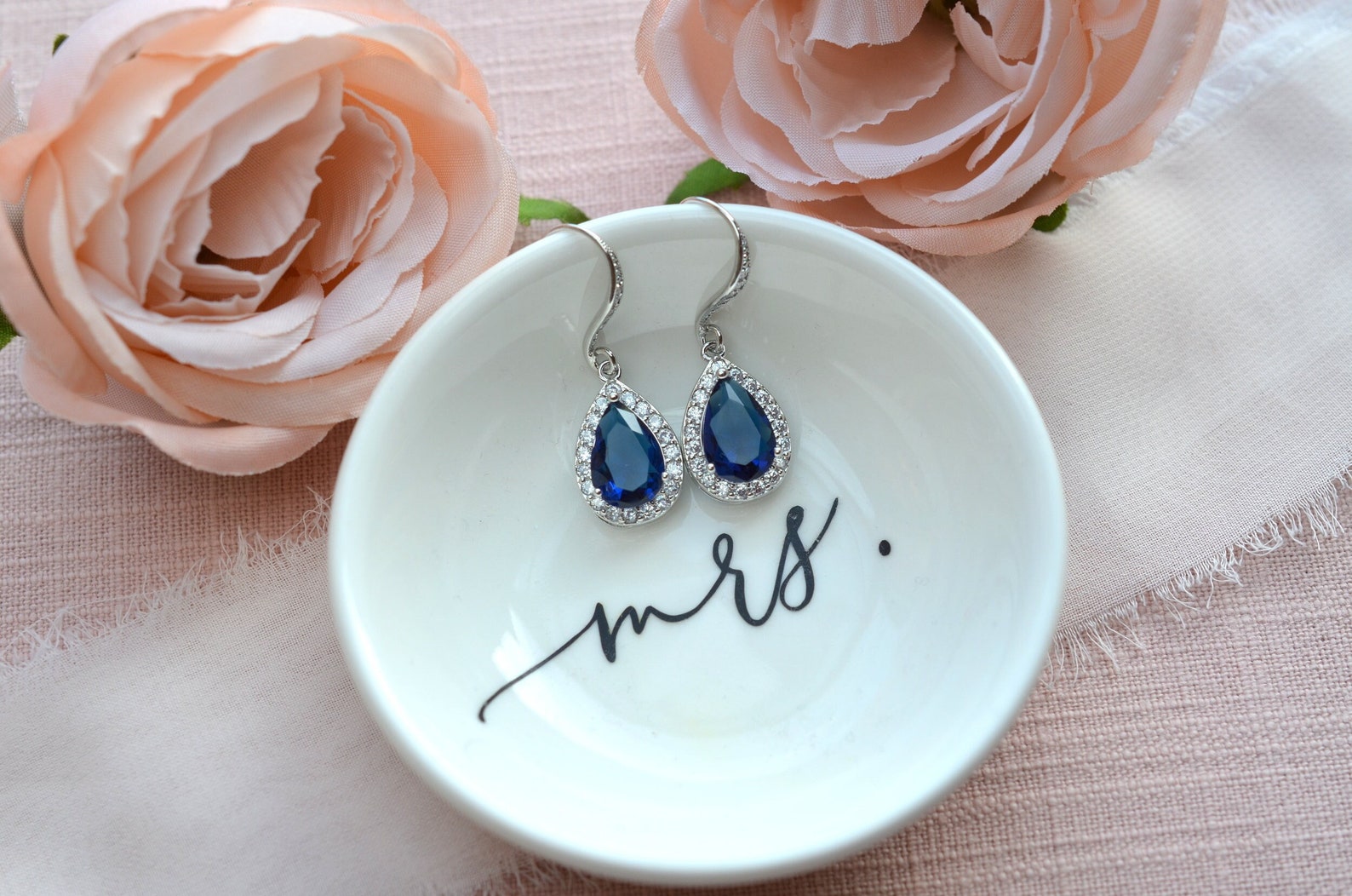 close-up blue sapphire earrings on a white ring dish