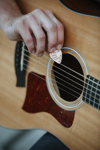 Man playing with personalized copper guitar pick